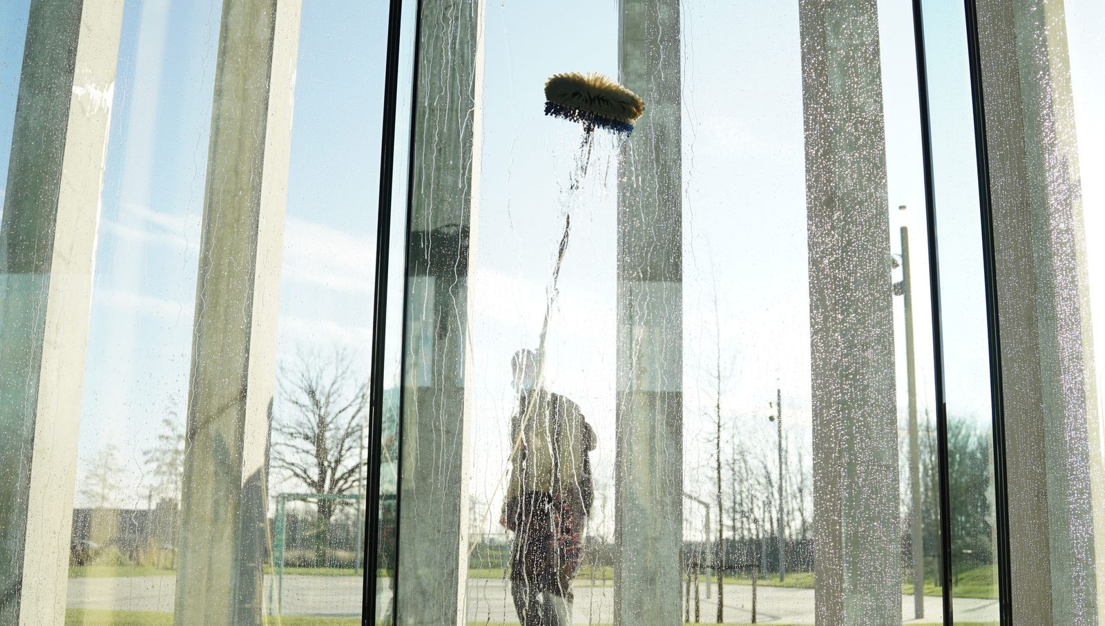 Glazen wand wordt gewassen met een telescopische borstel