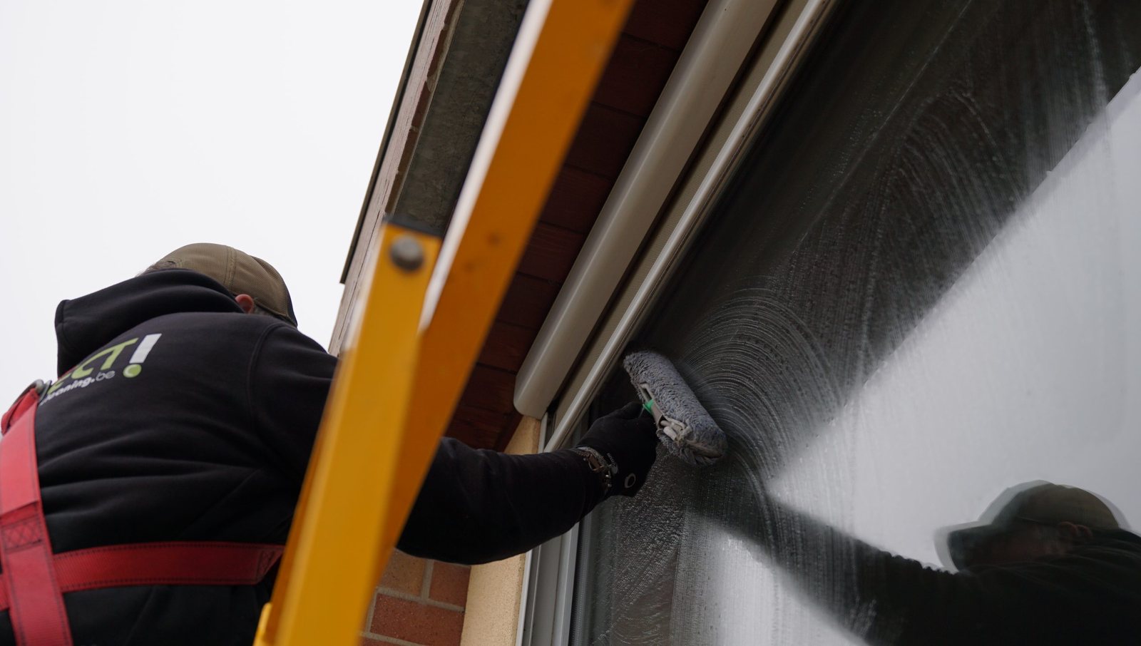 Medewerker reinigt een gevel vanop een hoogwerker